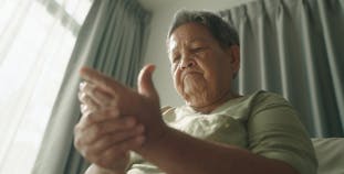 A woman grips her hand in pain from PsA.