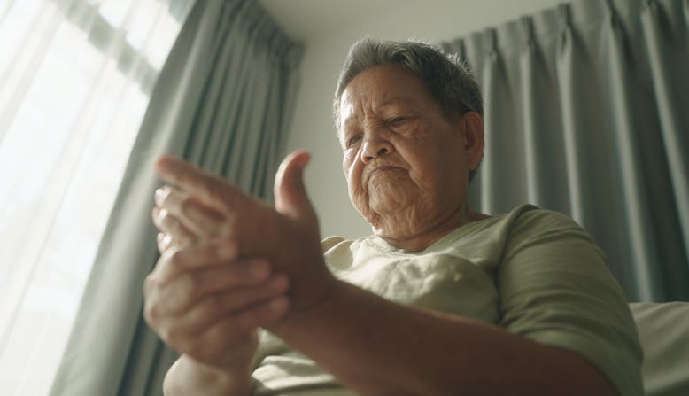 A woman grips her hand in pain from PsA.