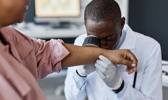 A doctor inspects a patient's skin.