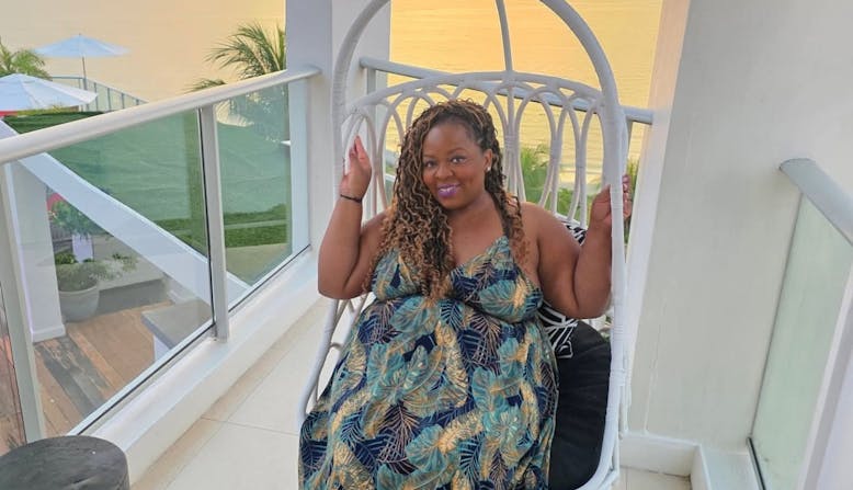 Ayesha Patrick sitting on a balcony with a sunset behind her.