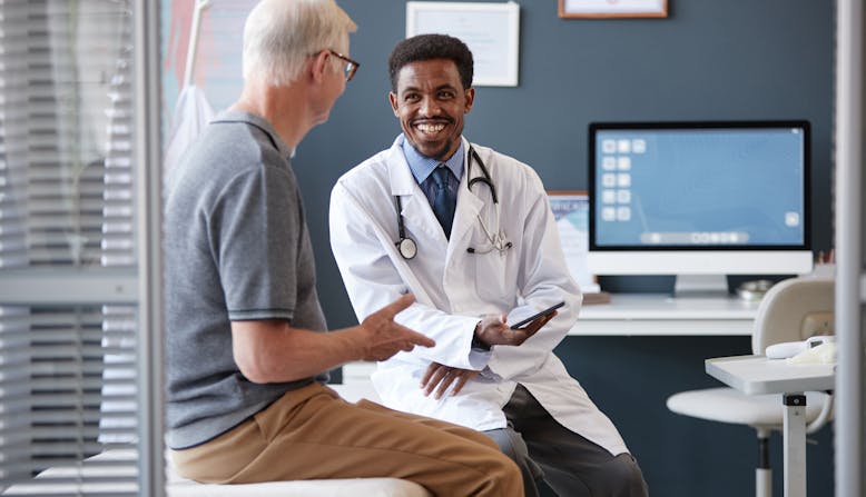 A doctor and a patient in an office smiling.