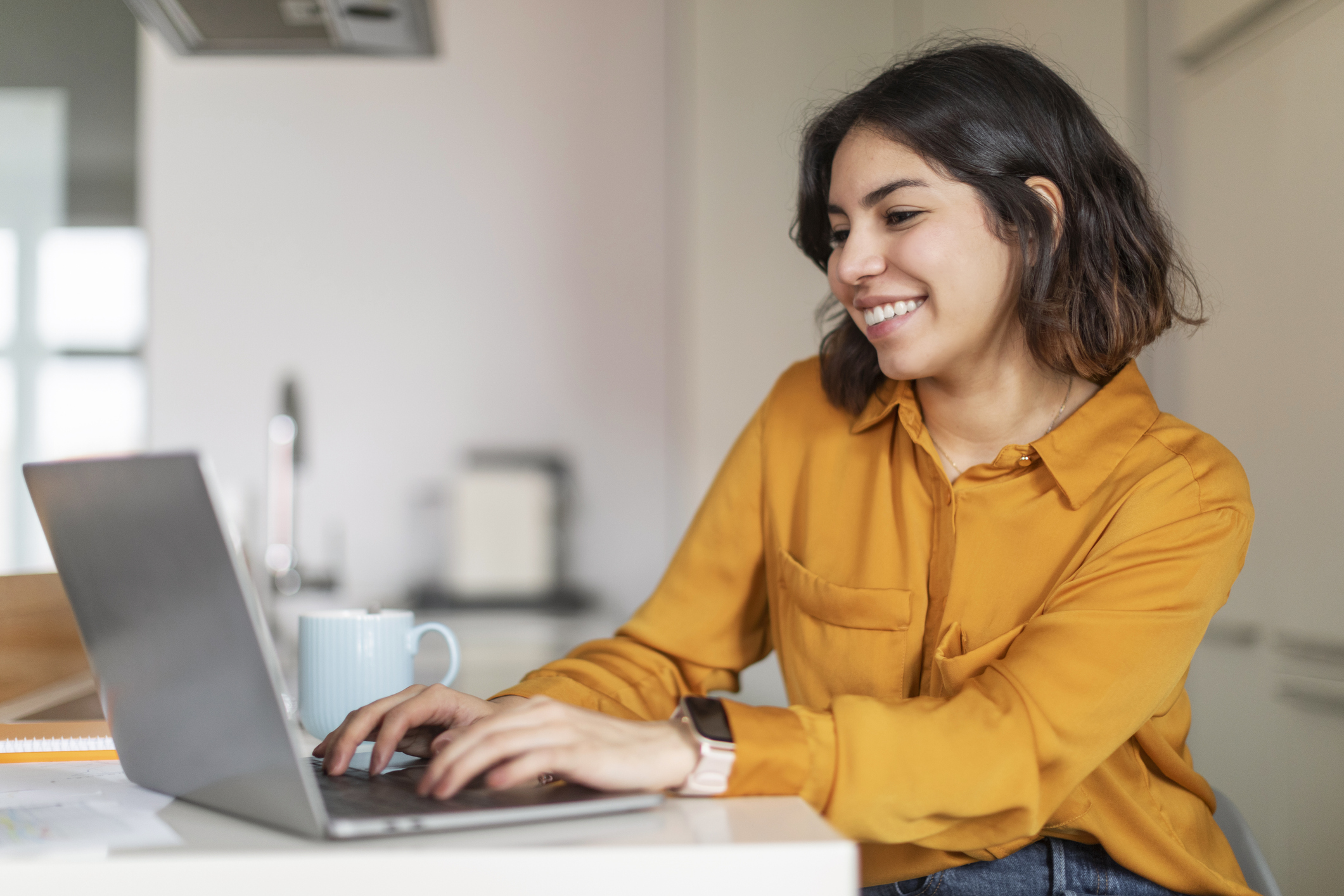 A woman smiling and working on a laptop computer.