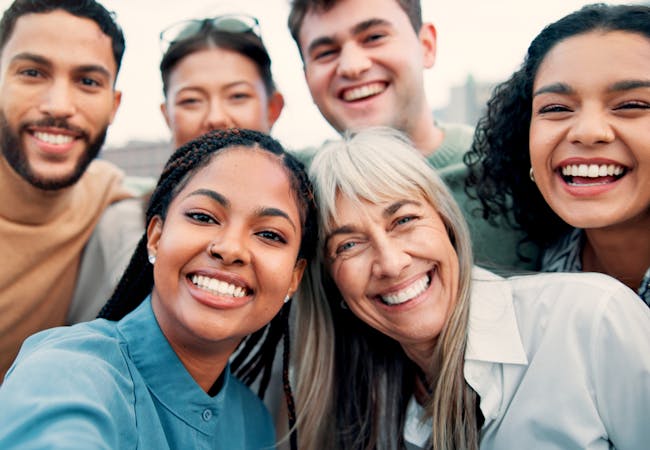 A diverse group of people smile for a selfie.