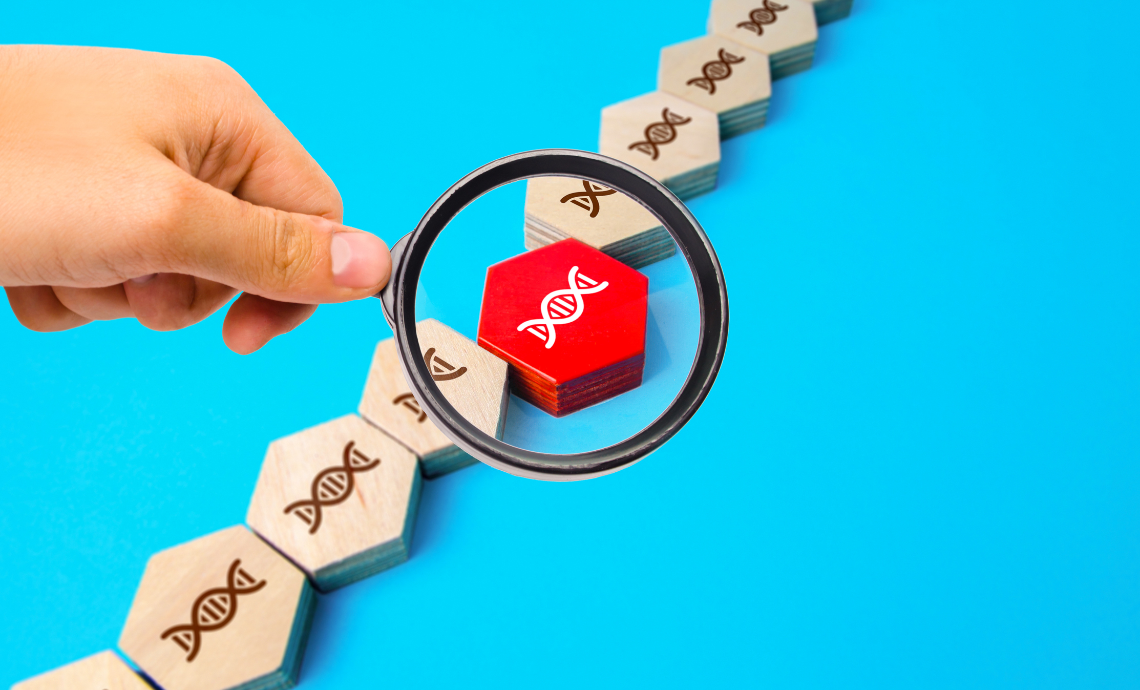 A magnifying glass focuses on a block with a DNA double helix.