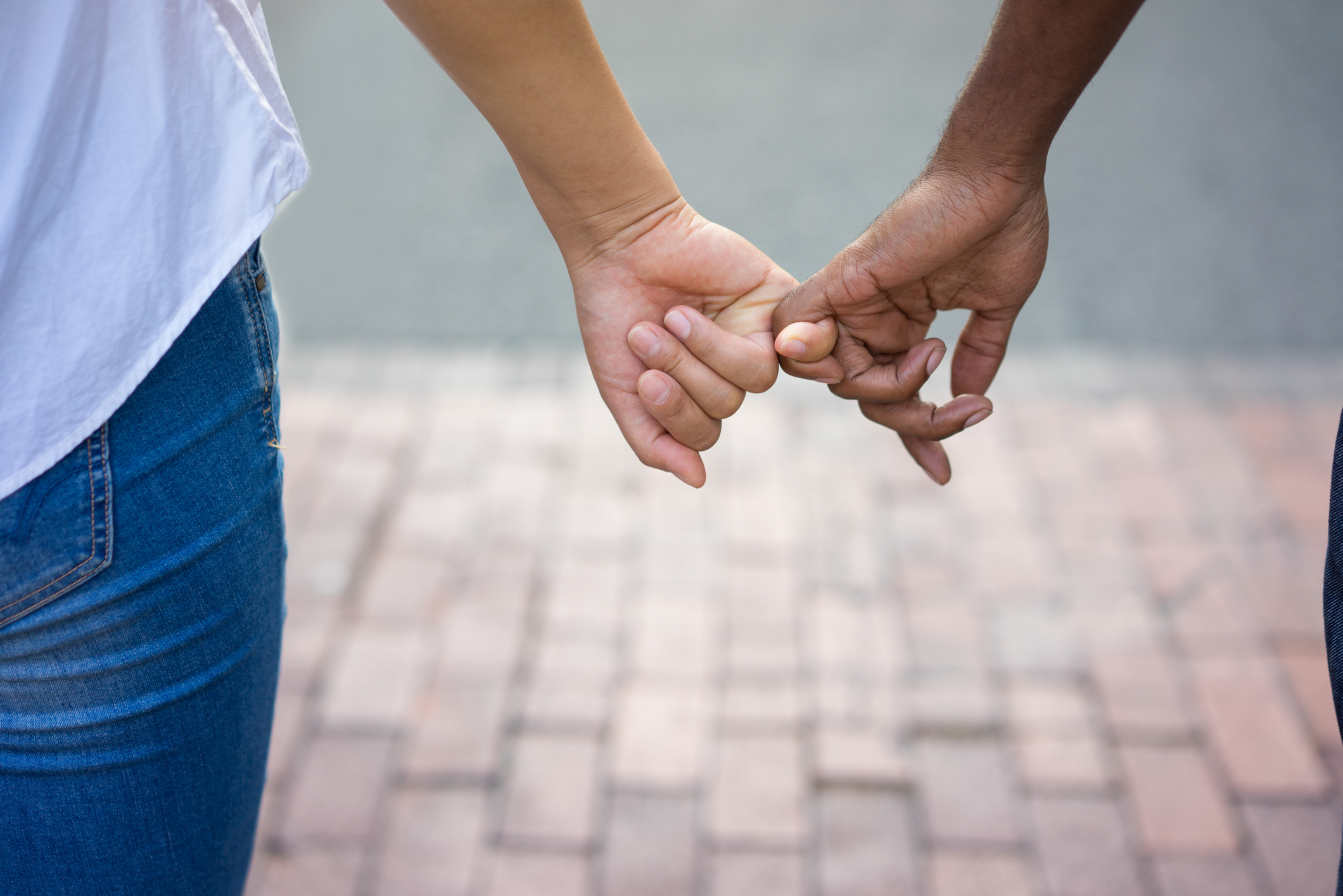 Two people holding hands outside.