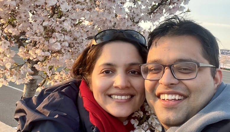 Rajesh Khanal and his wife standing near a blossoming cherry tree.