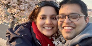 Rajesh Khanal and his wife standing near a blossoming cherry tree.