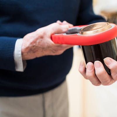 A man uses a jar gripper assistive device to open a jar.