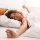 A woman looks refreshed and stretches after a good night's sleep