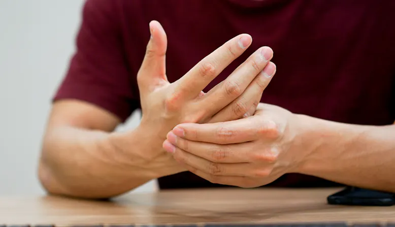 A man grips his hands in pain.