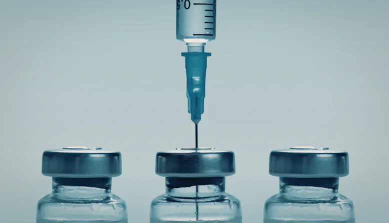A needle enters a vial of medicine.