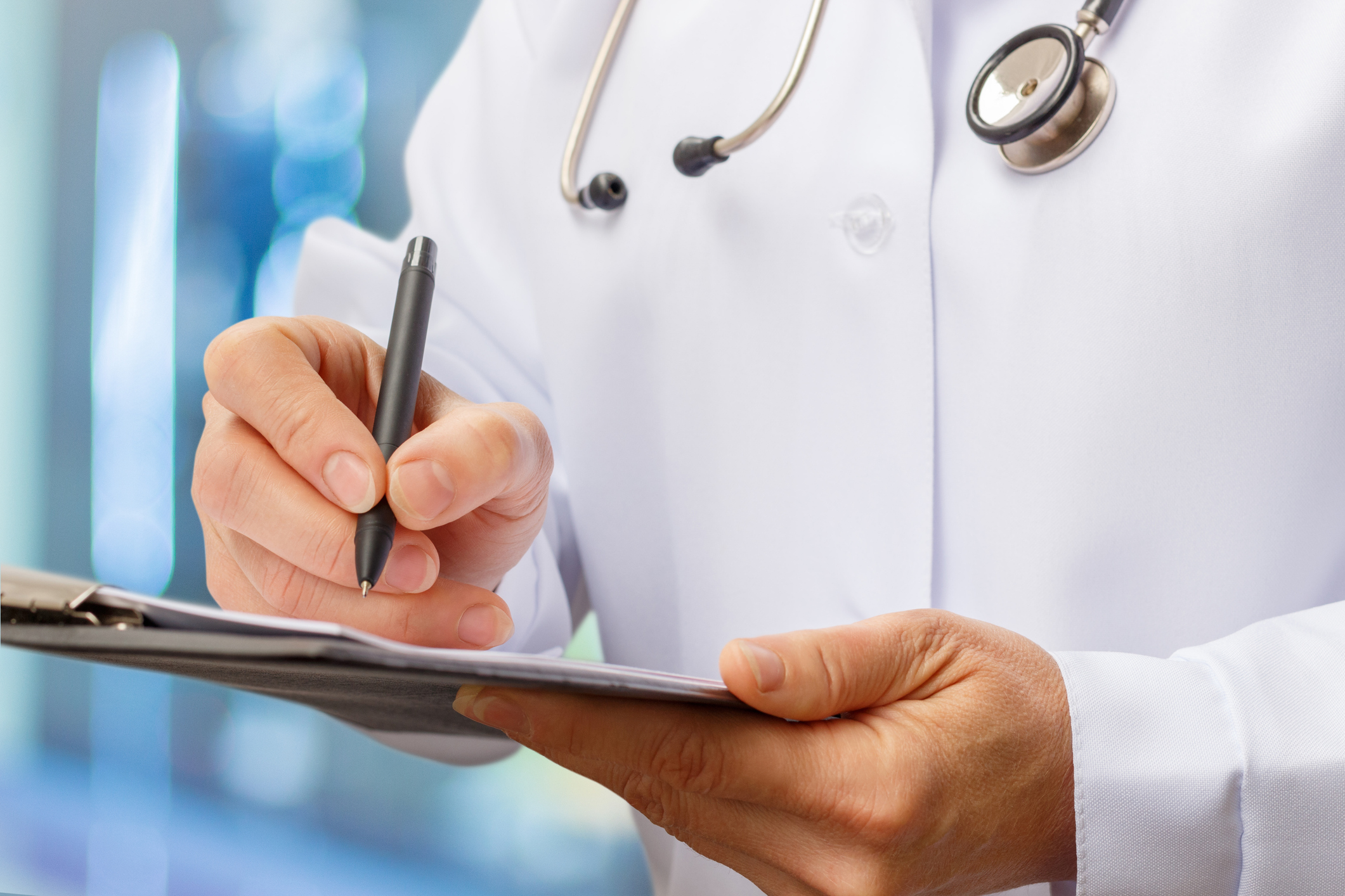 A doctor holds a pen over a clipboard.