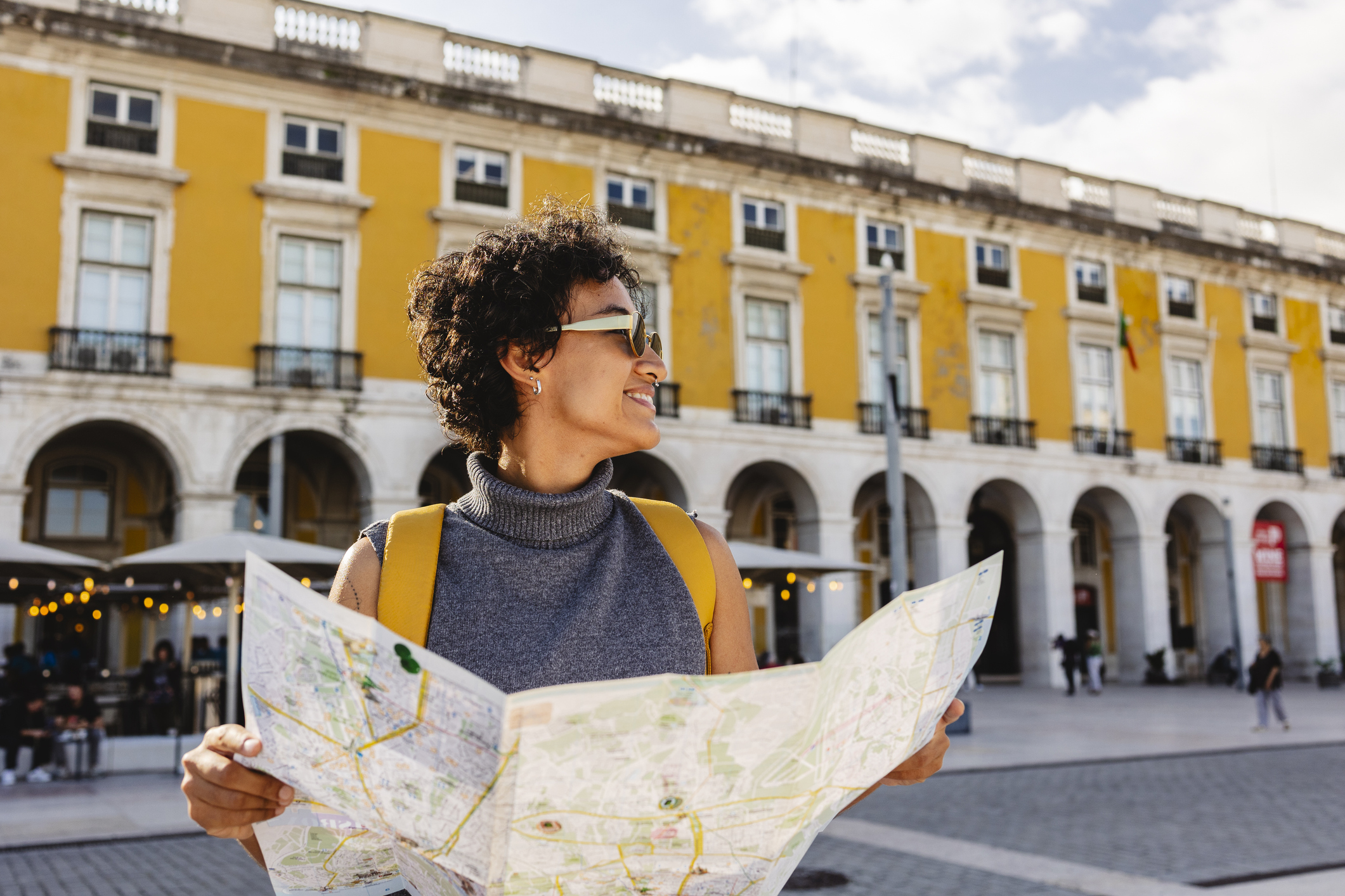 A woman looks at a paper map in a city on vacation.