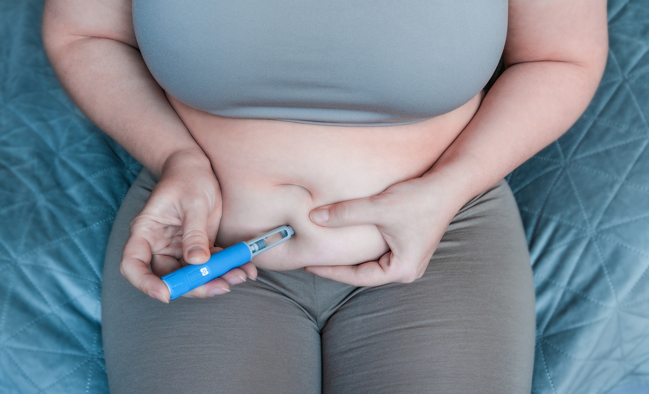 A woman injects her stomach.