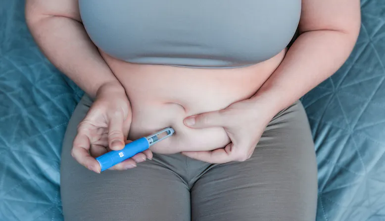 A woman injects her stomach.