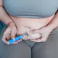 A woman injects her stomach.