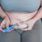 A woman injects her stomach.