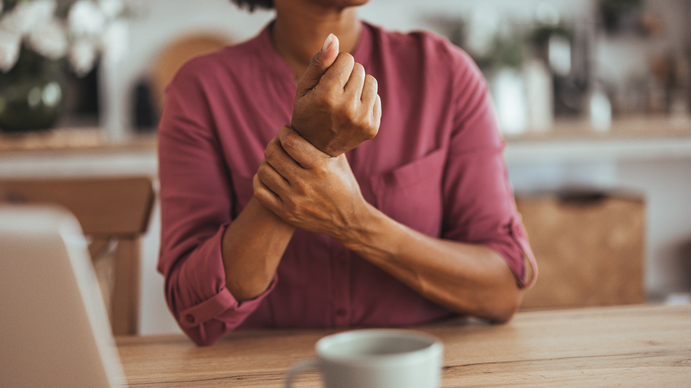 A woman holds her wrist in pain.