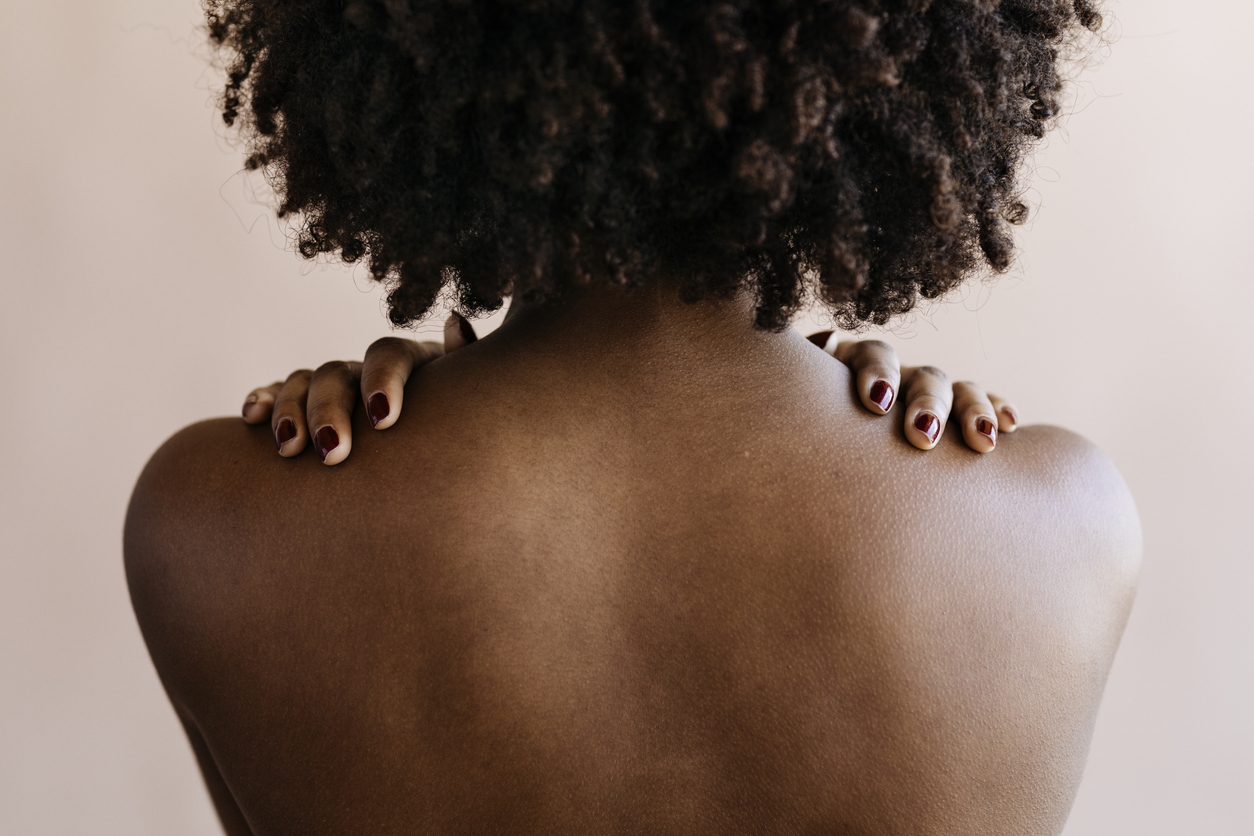 A woman with textured hair and skin of color shown from the back.