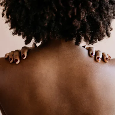 A woman with textured hair and skin of color shown from the back.