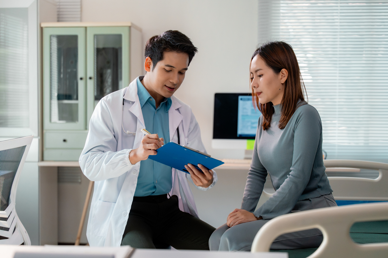 A doctor points to his clipboard to discuss with a patient.