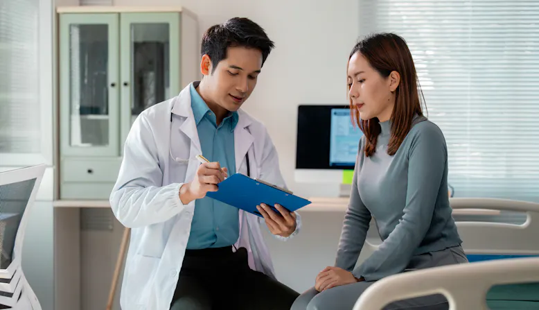 A doctor points to his clipboard to discuss with a patient.