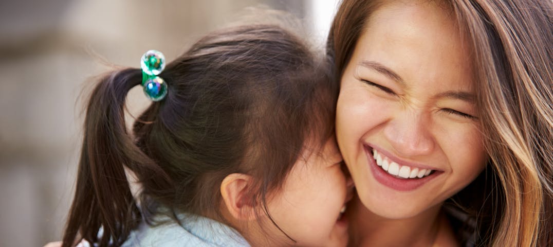 A mother and child embrace and smile together.