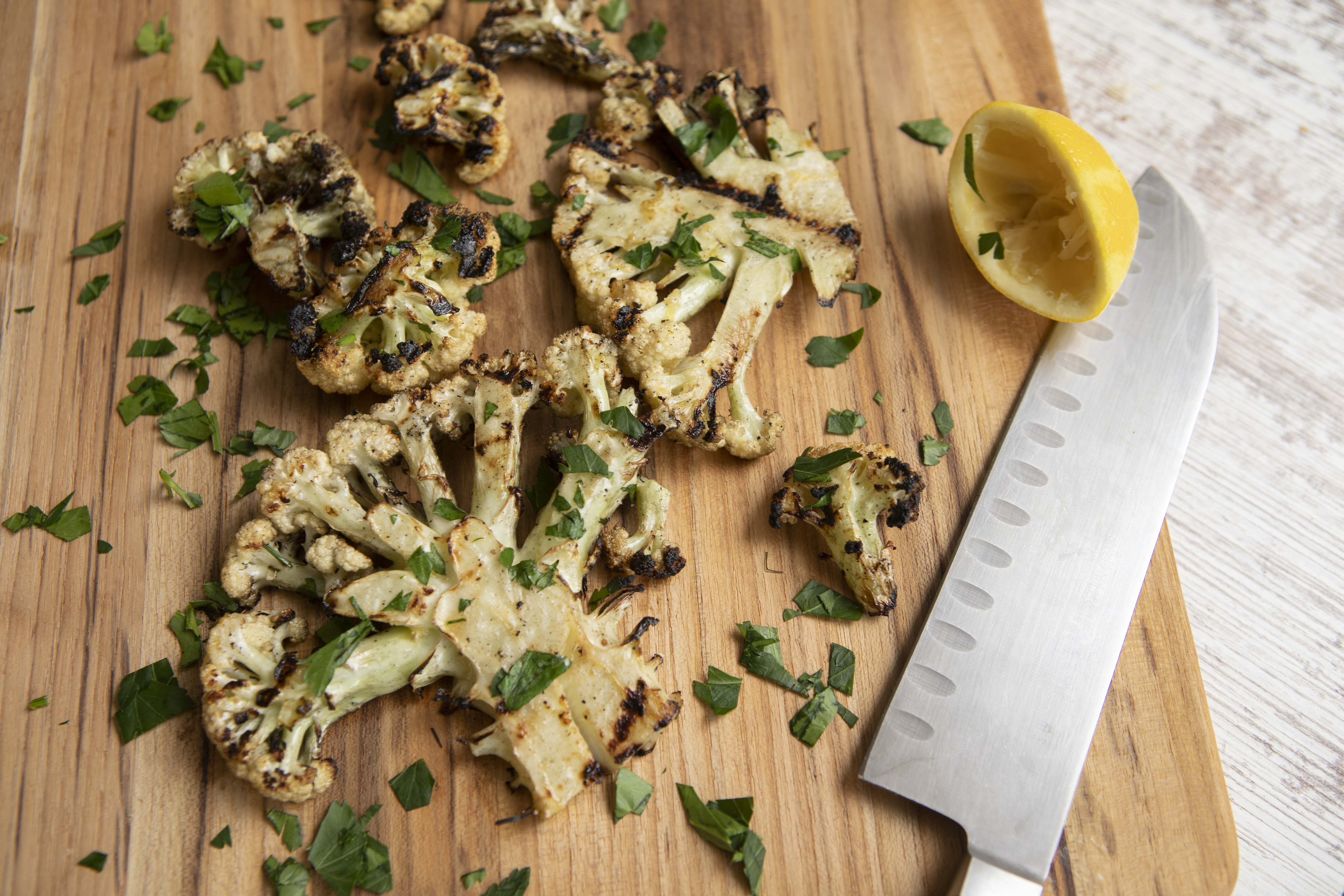 A cutting board with seasoned cauliflower and knife. 