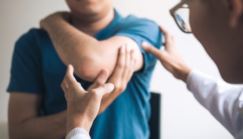 Patient holding arm while doctor examines it