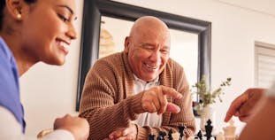 A senior man playing chess with others.