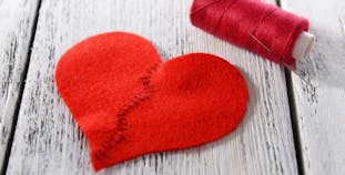 A felt heart mended in the middle with needle and thread.