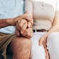 A couple sits on a bench holding hands.