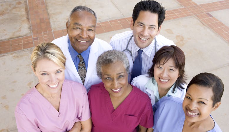 Group of doctors and nurses looking up at the camera and smiling.