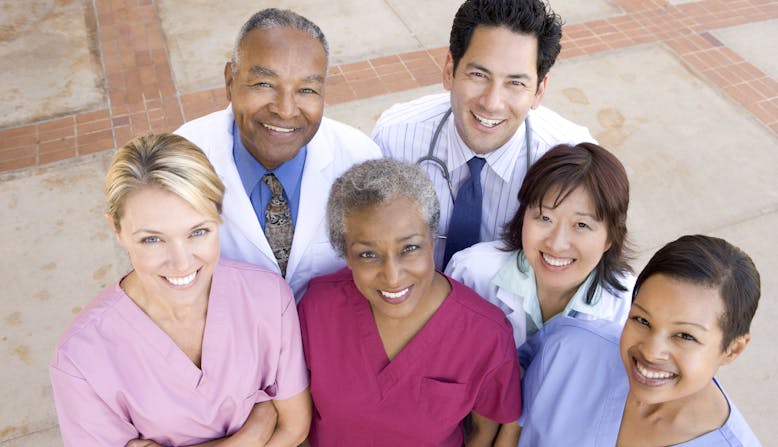 Group of doctors and nurses looking up at the camera and smiling.