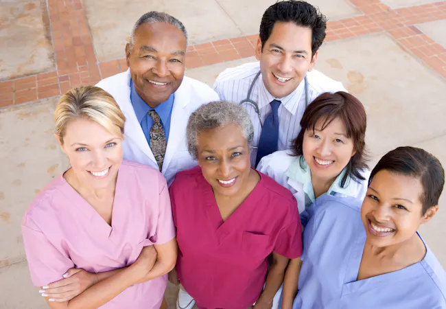 Group of doctors and nurses looking up at the camera and smiling.