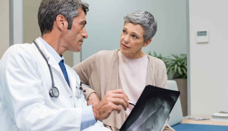 Photo of a rheumalologist examining an x-ray with a patient.