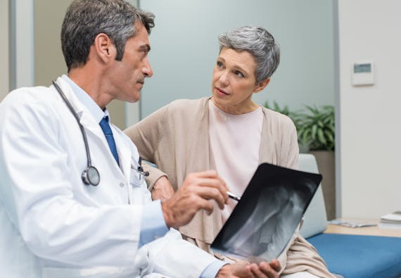 Photo of a rheumalologist examining an x-ray with a patient.