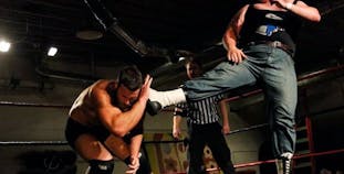 Michael Murray lands a kick on his opponent's head during a professional wrestling match. 
