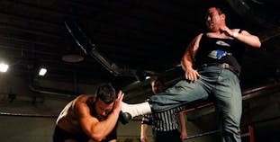 Michael Murray kicks his opponent in the wrestling ring.