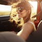 Young woman sits in the passenger seat of a car smiling.