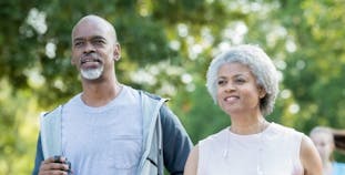 A man and a woman engage in a brisk walk outside.
