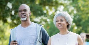 A man and a woman engage in a brisk walk outside. 