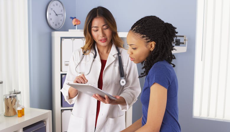 A doctor shows a patient information on a tablet while they are in an examination room.