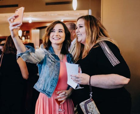 Two women pose for a selfie during an event.