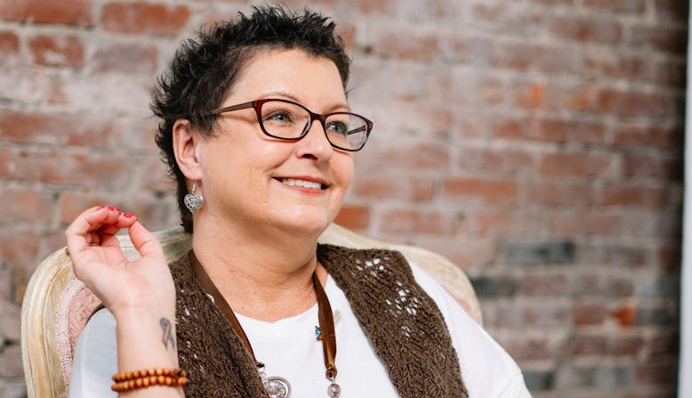 A woman with psoriasis sitting in a chair and smiling.
