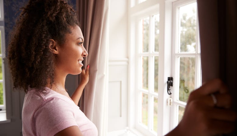 A woman looks out the window smiling.