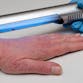 A hand with light skin and visible psoriasis on a surface with a gloved hand holding a phototherapy device above.
