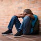 A boy sits outside of school after being bullied.