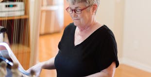 Carol Selby, NPF research ambassador, plays the piano and wears red glasses. 