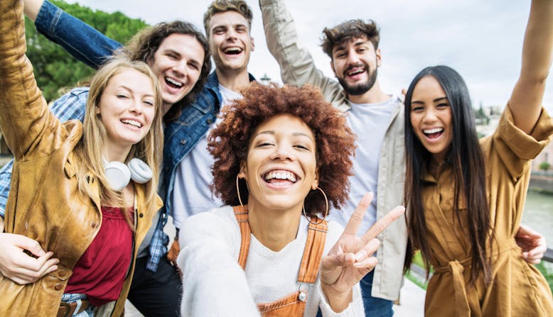 A multiracial group of young adults smiling and cheering.